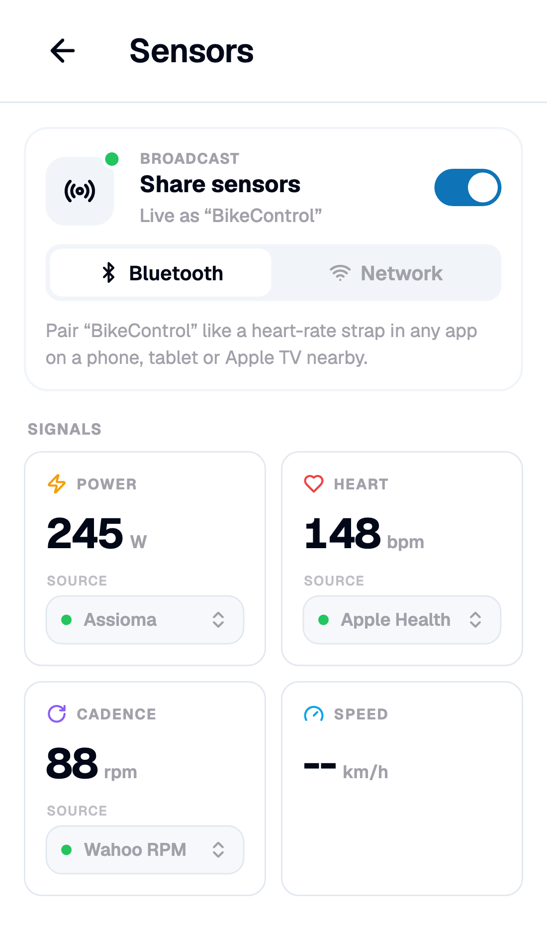 One switch. Everything you picked below it goes out as one device The Sensors page with the Share sensors switch on, reading Live as "BikeControl" over Bluetooth, and the Signals grid below: Power 245 W from an Assioma, Heart 148 bpm from Apple Health, Cadence 88 rpm from a Wahoo RPM